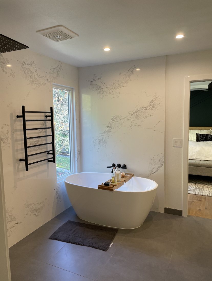 Finished bath with pale stone wall panels and a freestanding tub