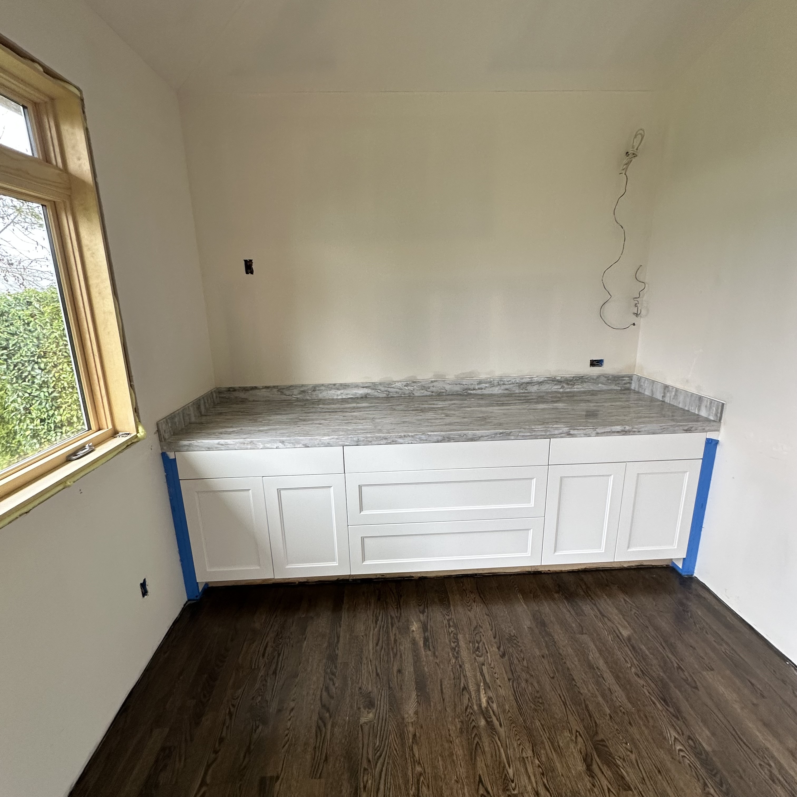 White shaker cabinetry with a gray patterned stone worktop and matching backsplash