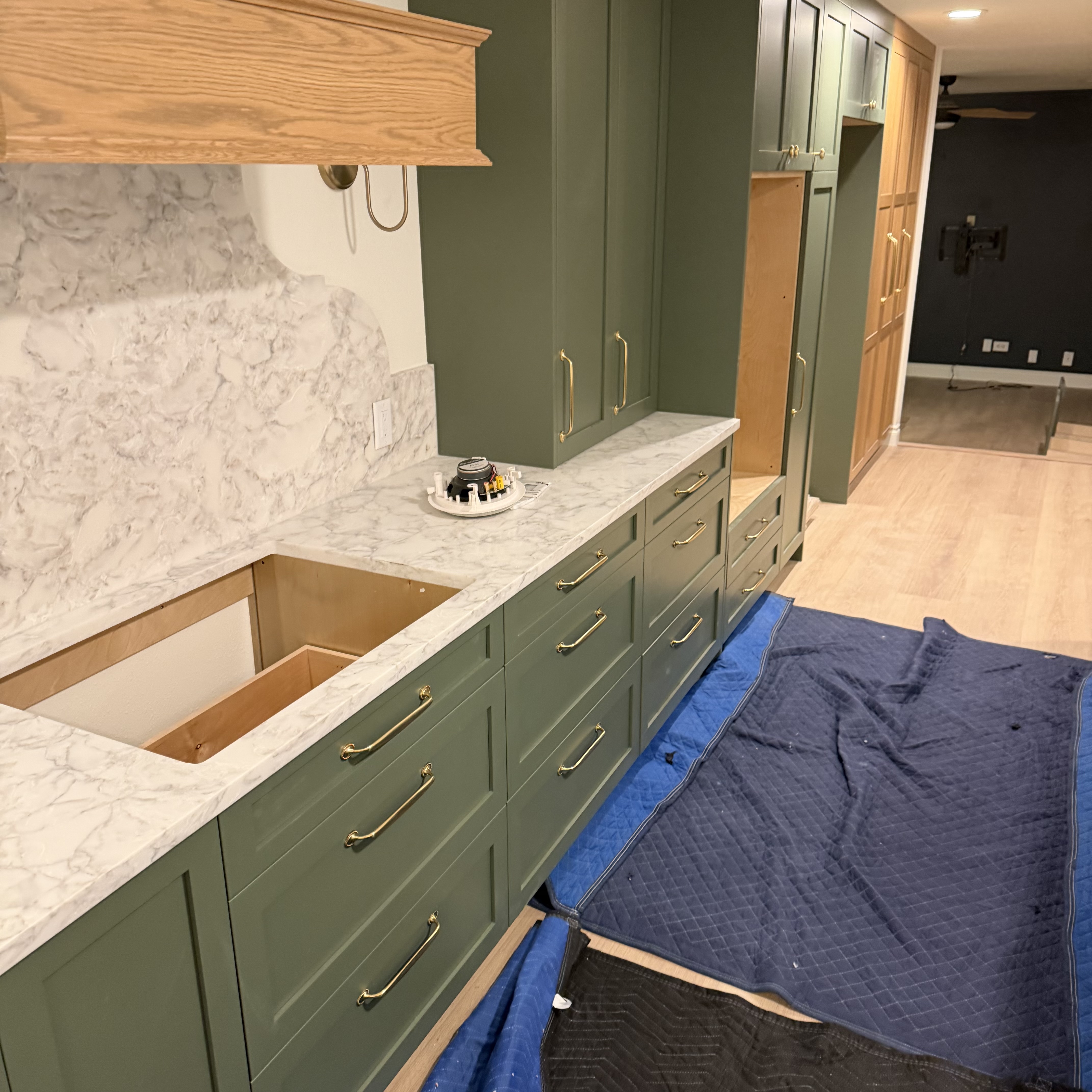 Green custom cabinetry with brass hardware and white patterned stone countertops