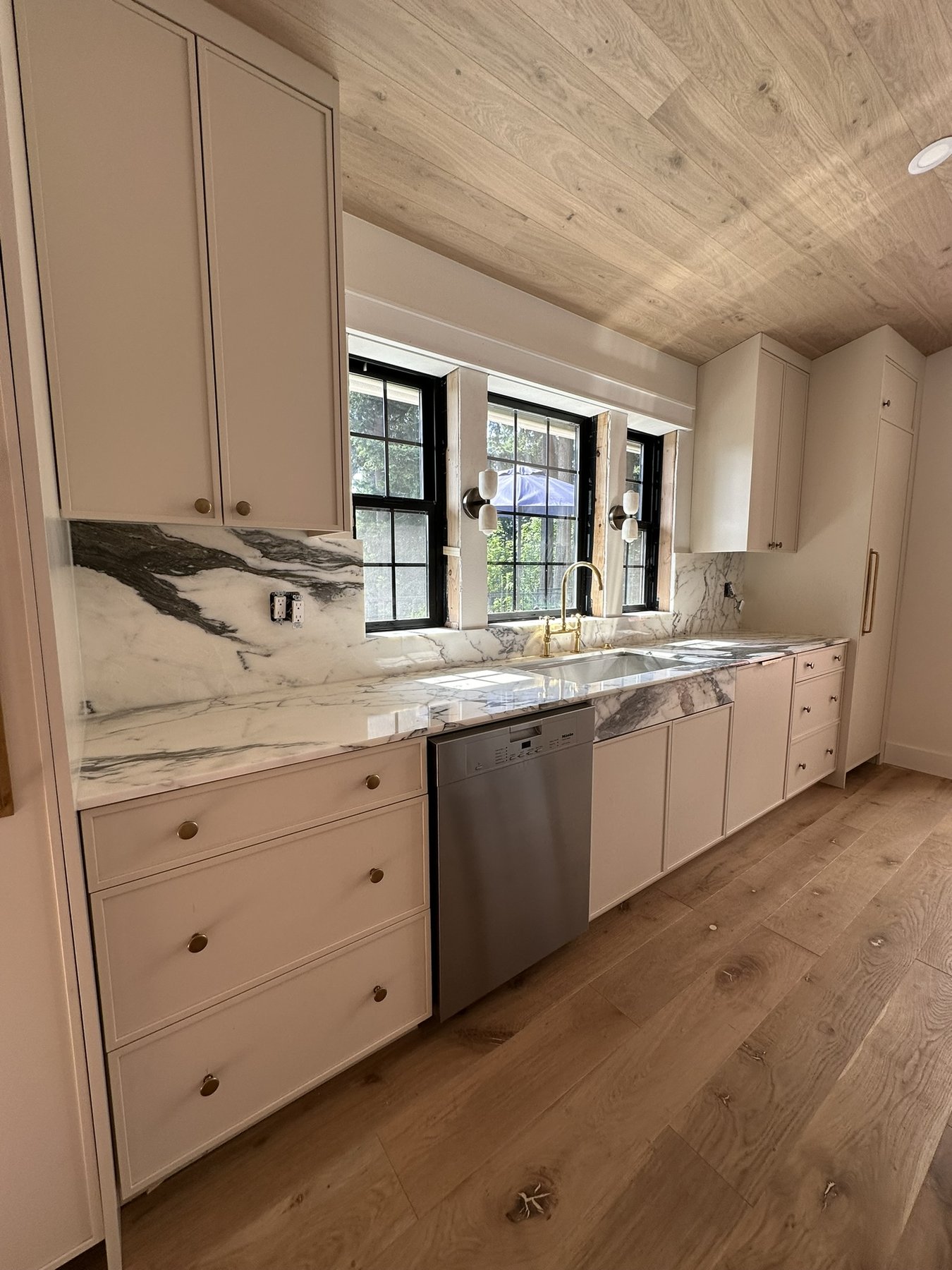 Natural marble countertops and full-height backsplash installed in a bright custom kitchen