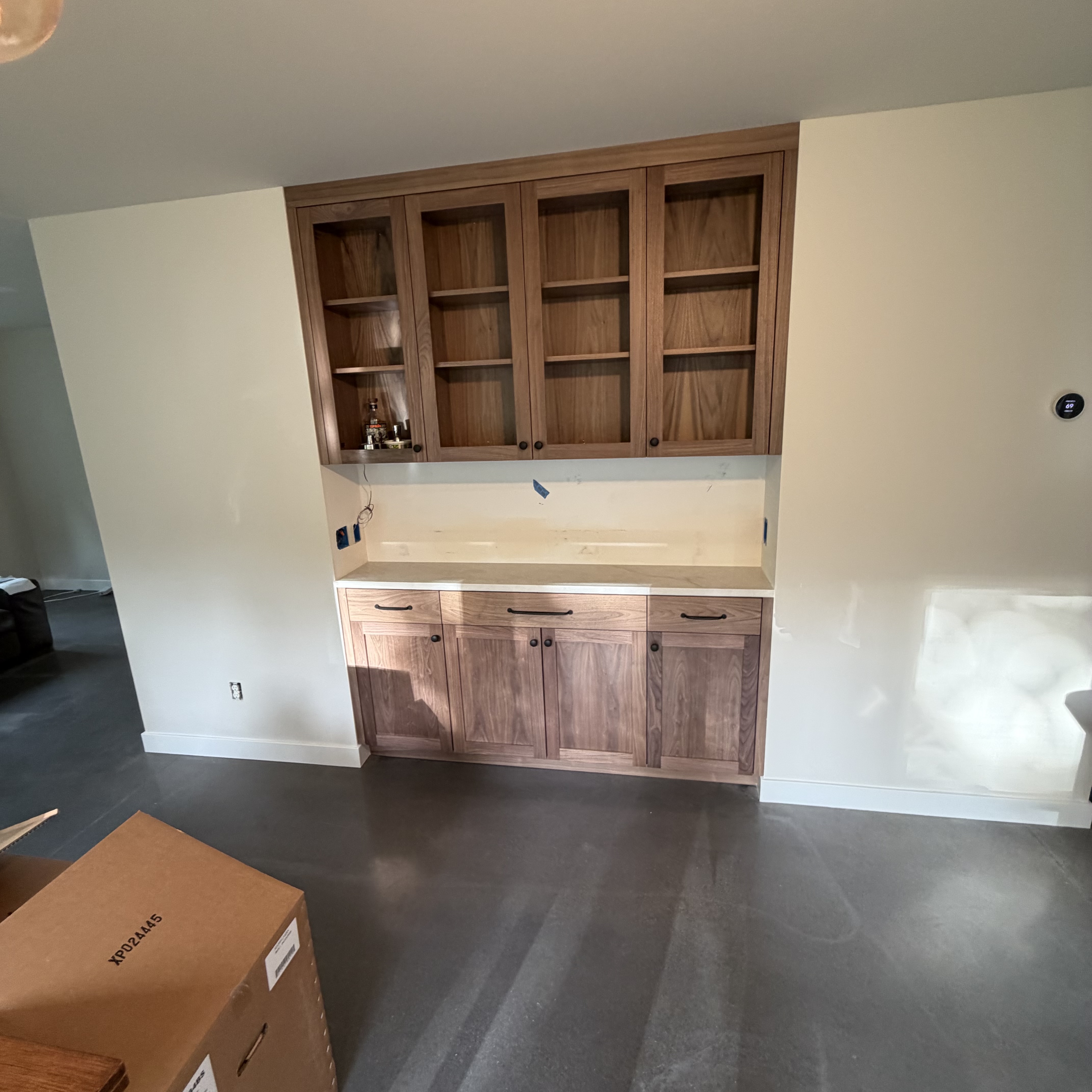 Custom walnut built-in cabinetry with glass-front upper doors and a pale stone counter