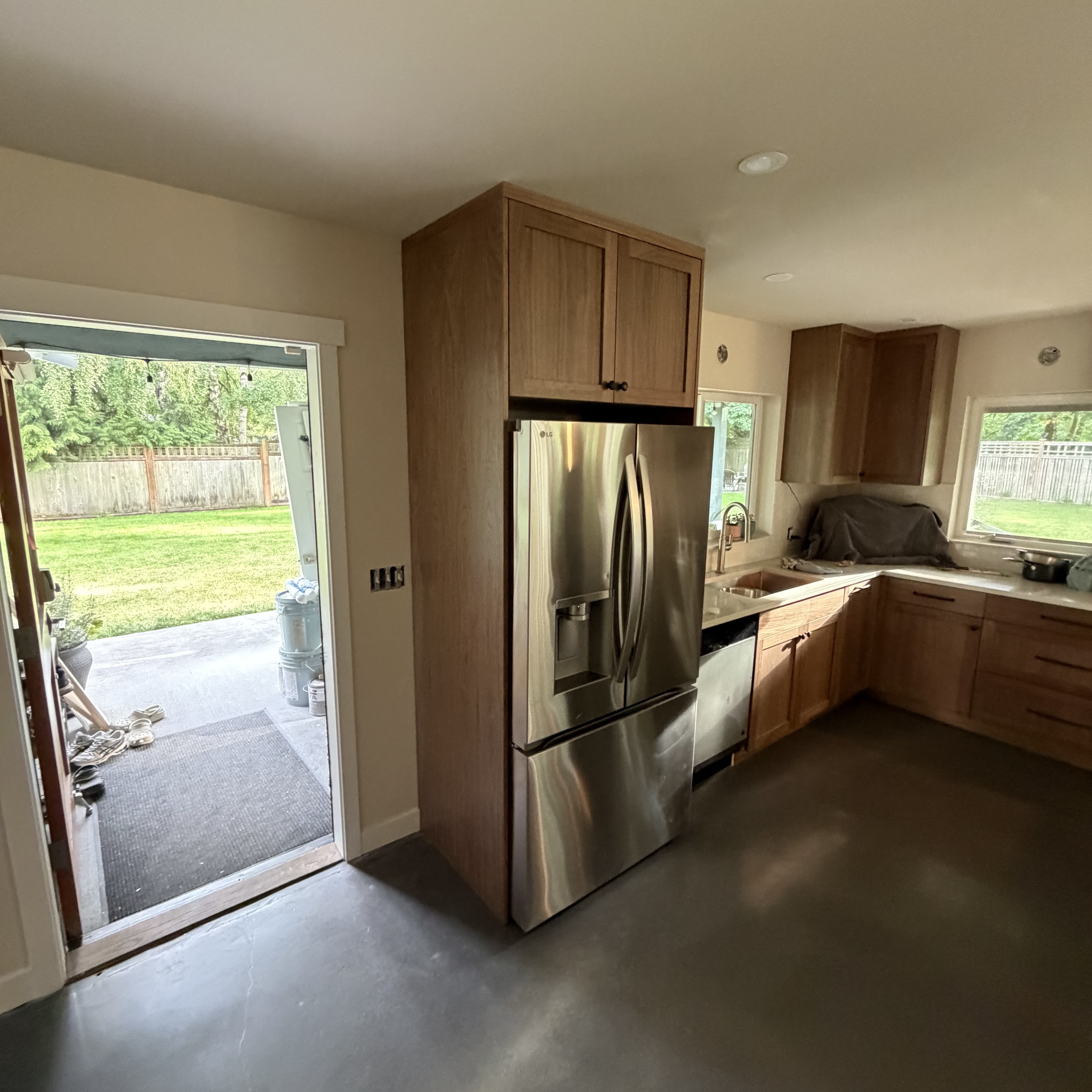 Warm walnut kitchen cabinetry fitted around stainless steel appliances and stone countertops